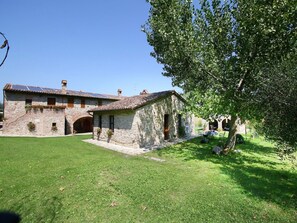 A stone building with a tiled roof, a grassy yard, and a tree. - Cottage in Todi with Pool and Sauna (Todi)