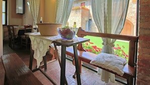 Eine gemütliche Terrasse mit einer Holzbank, einem Tisch mit weißer Tischdecke und einem Blumentopf.