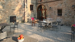 Une terrasse extérieure avec des murs en pierre, une table en bois et des chaises.
