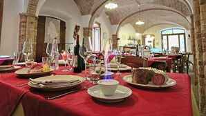 Un restaurant avec des arches en briques et des nappes rouges.
