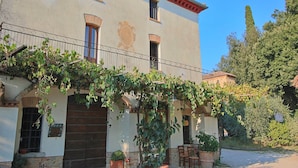 Un bâtiment à deux étages doté d’un balcon, d’une entrée en pierre et de plantes en pot.
