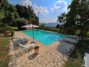 A swimming pool with lounge chairs and a pergola.