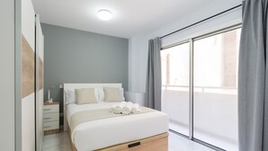 Une chambre moderne avec un lit, une table de chevet et une grande fenêtre avec des rideaux.