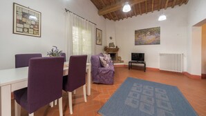 A dining area with a table and chairs, a sofa, a fireplace, and a television. - Escape in Rosignano Hills (Rosignano Marittimo)