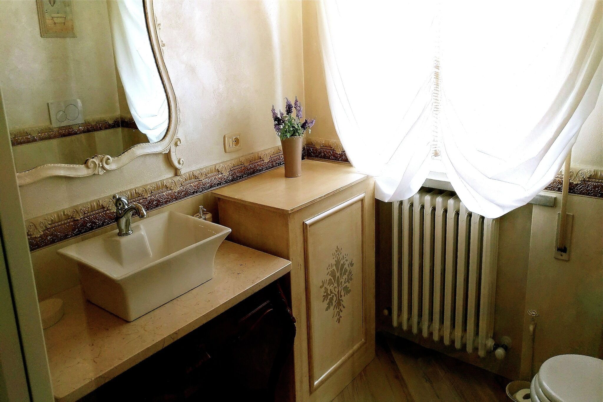 A bathroom with a sink, mirror, and a radiator.