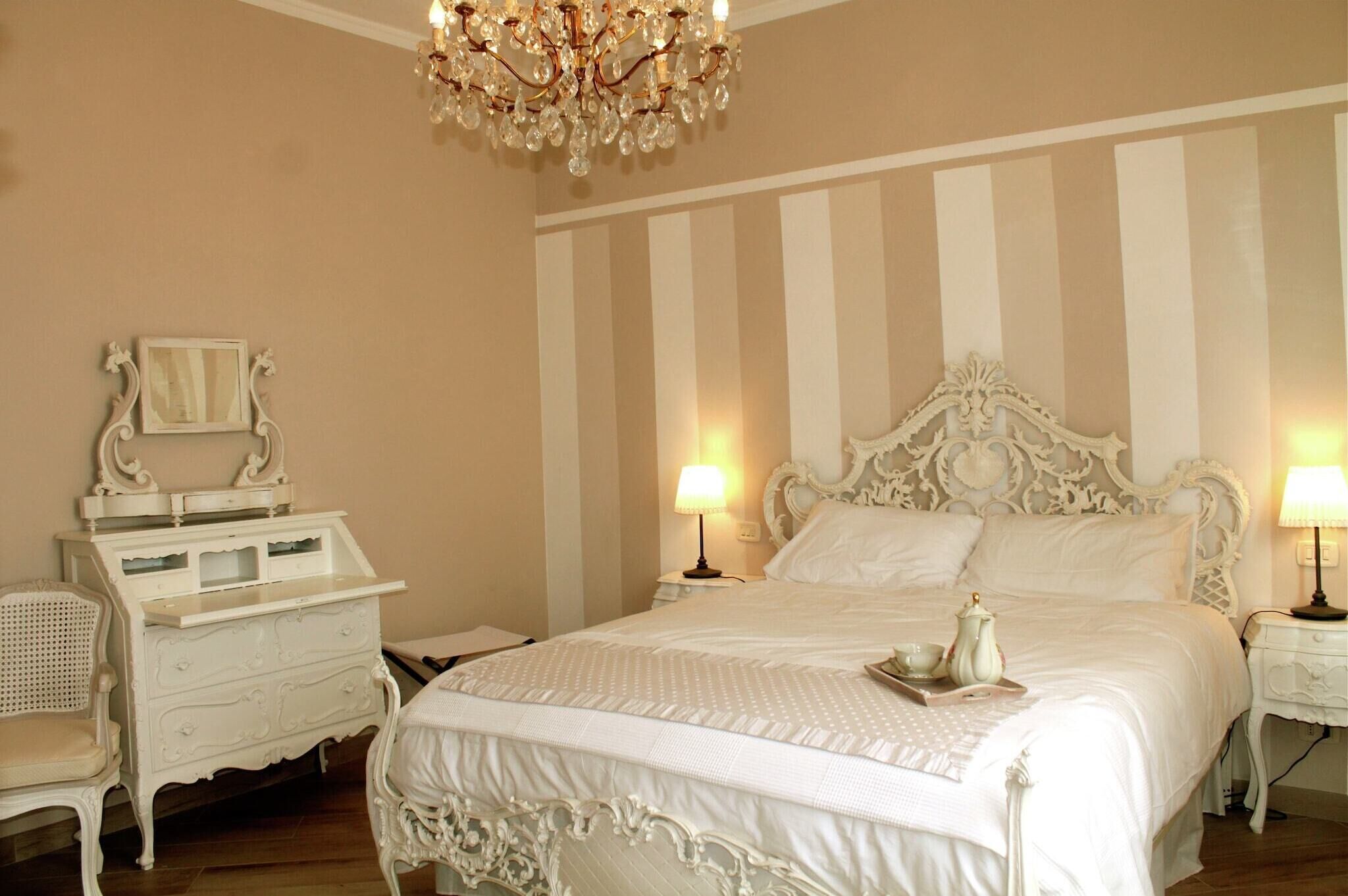 Une chambre à coucher avec un grand lit, deux tables de chevet avec des lampes, une commode et une chaise.