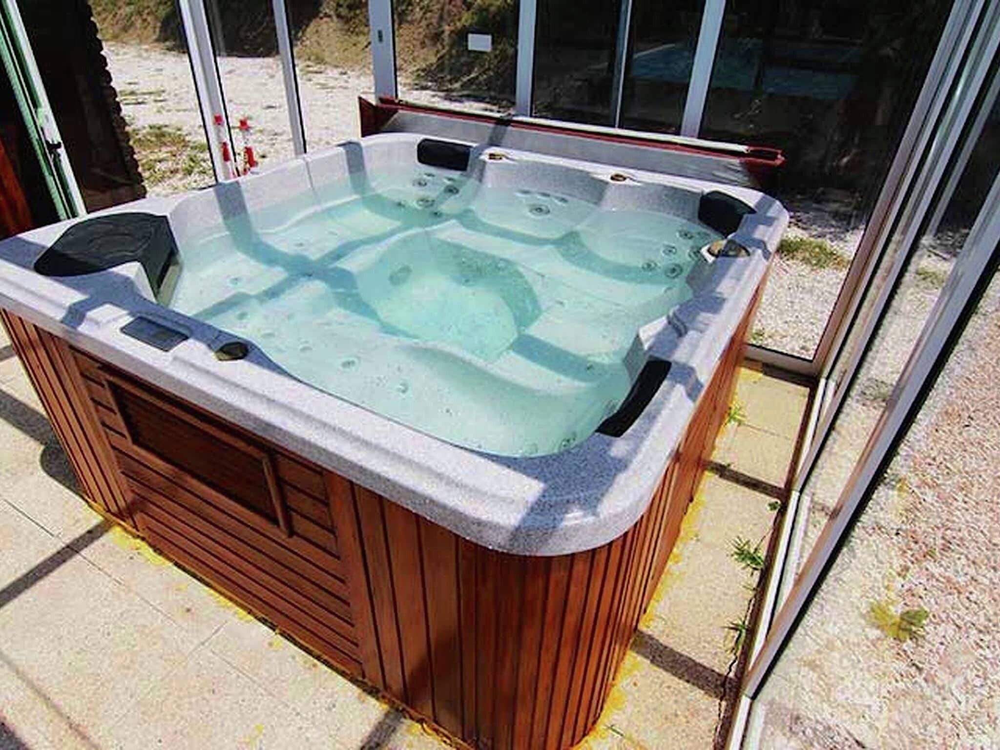 A hot tub with a wooden exterior and a glass enclosure.