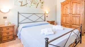 A bedroom with a bed, wooden wardrobe, bedside tables, and a wall-mounted artwork. - Farmhouse in Apecchio with Panoramic Views (Apecchio)