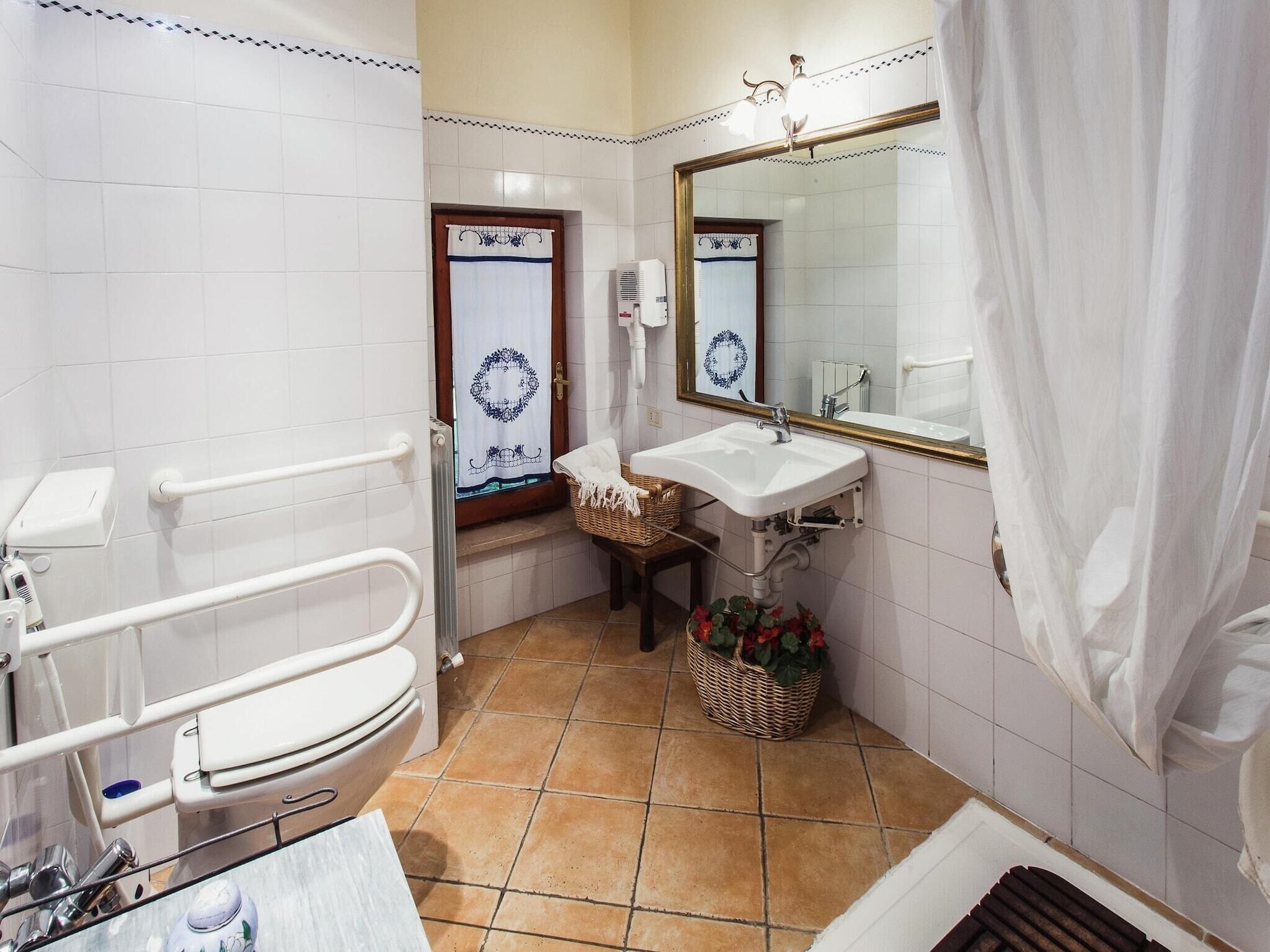 Un baño con inodoro blanco, lavamanos, espejo y cortina de ducha.