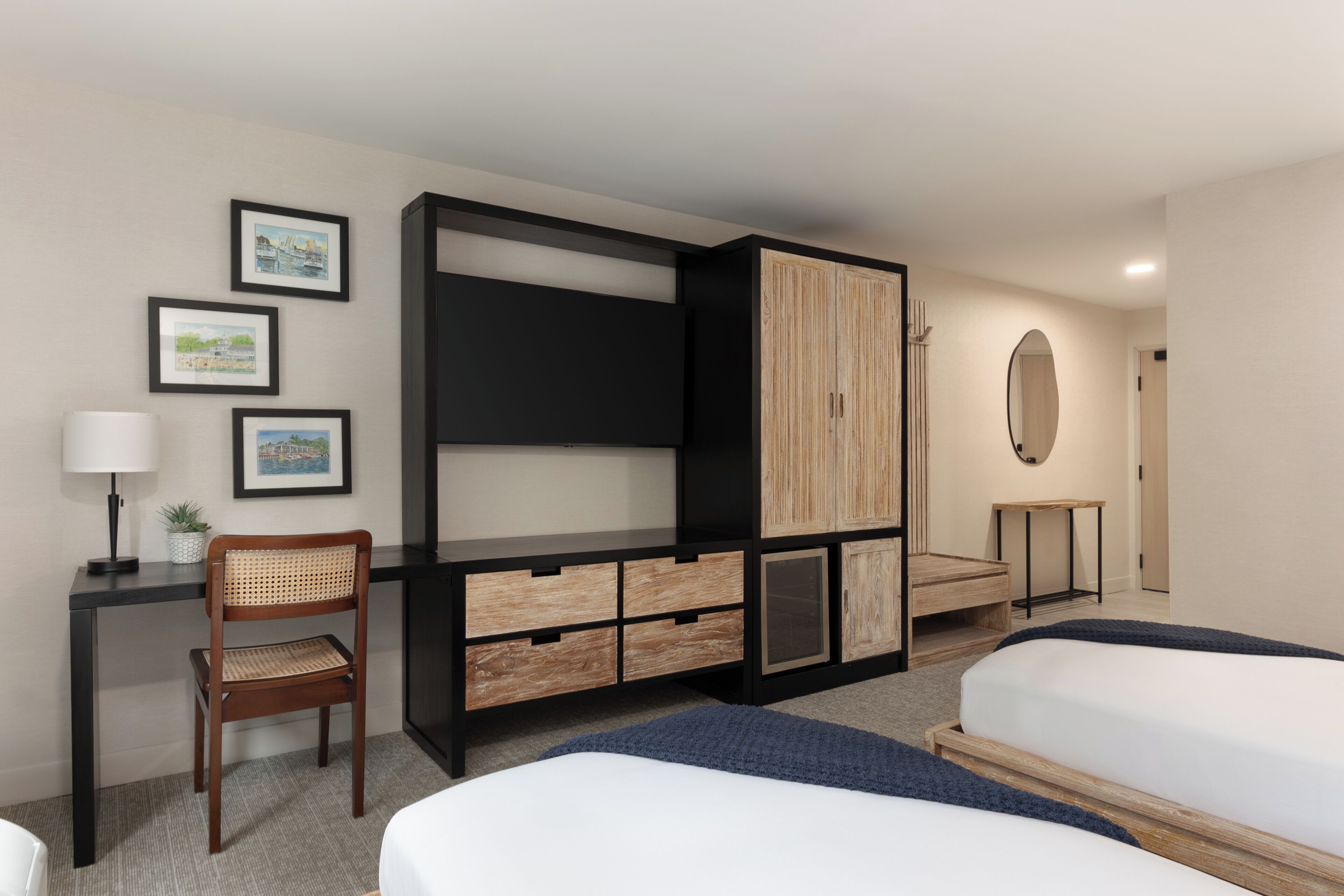 A hotel room with a bed, a desk with a chair, a wardrobe, and a small table.