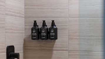 A bathroom with three black bottles of Zenology products on a tiled wall.