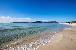 A beach with clear water, a sandy shore, and distant hills. - San Marino Poolside Stay (Passano di Coriano)
