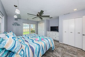 A bedroom with a bed, a ceiling fan, a TV, and a wardrobe.