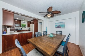 A modern kitchen with wooden cabinets, a central island, and a dining area with a wooden table and chairs.