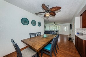 A dining area with a wooden table, chairs, and a ceiling fan.