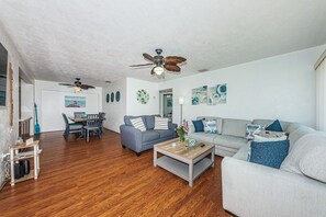A spacious living area with a dining table, two sofas, a coffee table, and a ceiling fan.