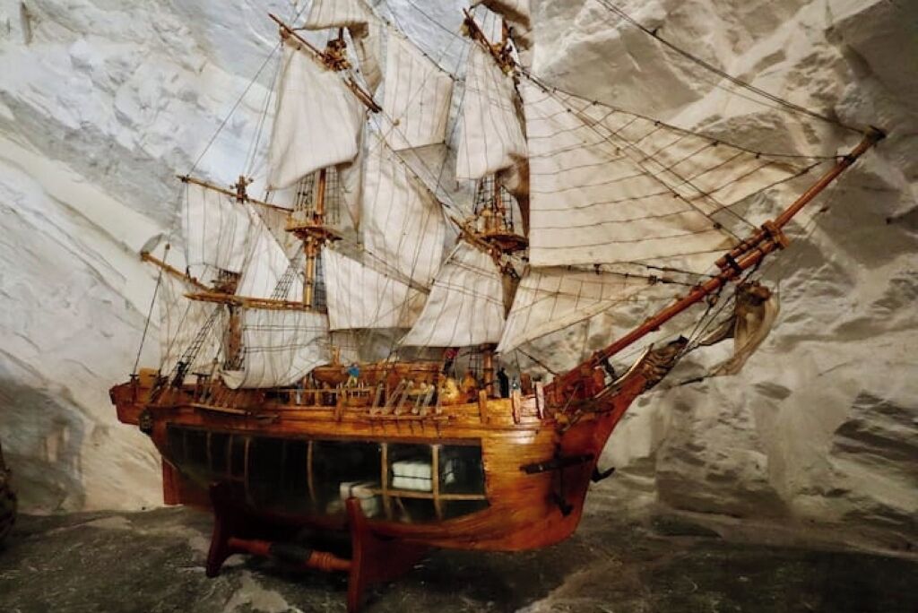 Une maquette de navire dotée de plusieurs voiles et d’une coque en bois, exposée dans un musée.