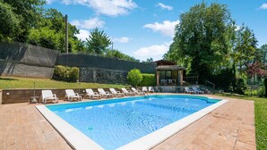 A rectangular swimming pool with a tiled deck, surrounded by white lounge chairs and a covered seating area. - Holiday Home in Sellano with Pool & Sun Terrace (Sellano)