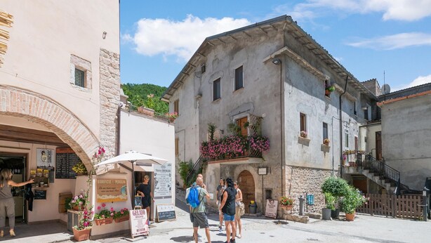 A historic building with a stone facade, a balcony with flowers, and a signboard. - Holiday Home in Sellano with Pool & Sun Terrace (Sellano)