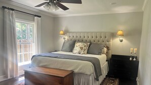 A bedroom with a tufted headboard, a wooden bench, a patterned rug, and a nightstand with candles. - Charming Ranch - Near it All in East Dallas! (Dallas)