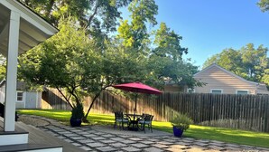 A patio with a wooden deck, a red umbrella, and a table with chairs. - Charming Ranch - Near it All in East Dallas! (Dallas)