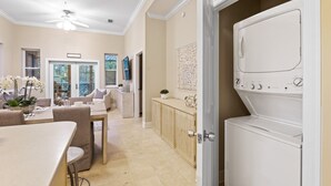 A modern kitchen with a built-in oven, a dining area with a table and chairs, and a laundry area with a washing machine. - New List 3BR/2BA Golf Cart - 6 seater Walk to Beach Top of the Dune (Santa Rosa Beach)