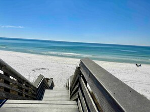 A wooden boardwalk leading to a beach with a clear view of the ocean.