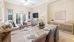 A dining area with a long table set for four, a ceiling fan, and a view of the outdoors. - New List 3BR/2BA Golf Cart - 6 seater Walk to Beach Top of the Dune (Santa Rosa Beach)