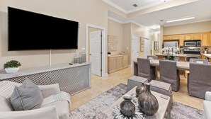 A modern living room with a flat-screen TV, a sofa, and a coffee table with decorative items. - New List 3BR/2BA Golf Cart - 6 seater Walk to Beach Top of the Dune (Santa Rosa Beach)