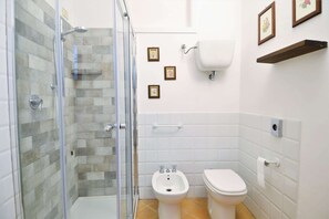 Un baño con ducha de vidrio, un bidé, un inodoro y un lavamanos.