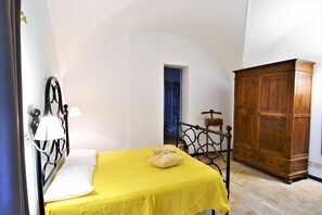 Una habitación con una cama, un armario de madera y un ventanal pequeño.