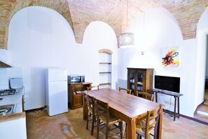 Una cocina amplia con una mesa y sillas de madera, un refrigerador, un microondas y un televisor.