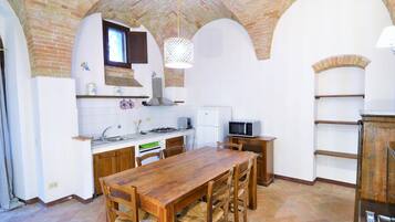 A kitchen with a wooden table and chairs, a microwave, and a stove.