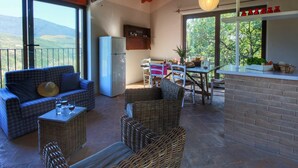 A spacious living area with a sofa, wicker chairs, a dining table, and a kitchen area. - Holiday home with pool near Assisi (Assisi)