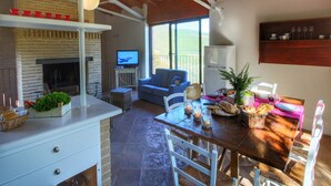 A cozy dining area with a table set for two, a fireplace, and a television in the background. - Holiday home with pool near Assisi (Assisi)