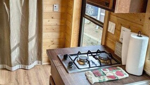 Una cucina compatta con pareti in legno, un fornello a gas, un lavello e una finestra con vista.