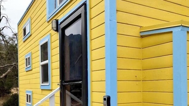 Un edificio giallo con decorazioni blu, una porta e una piccola finestra.