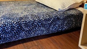 Una piccola stanza in una baita di legno con un letto singolo, soffitto in legno e pavimento in legno.