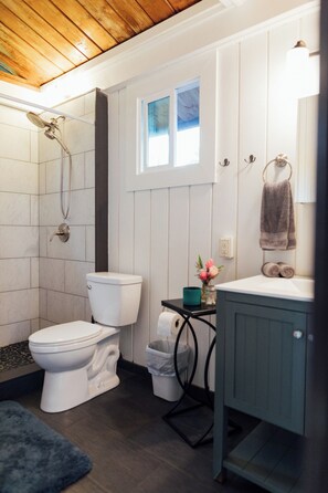 A bathroom with a toilet, shower, and sink.