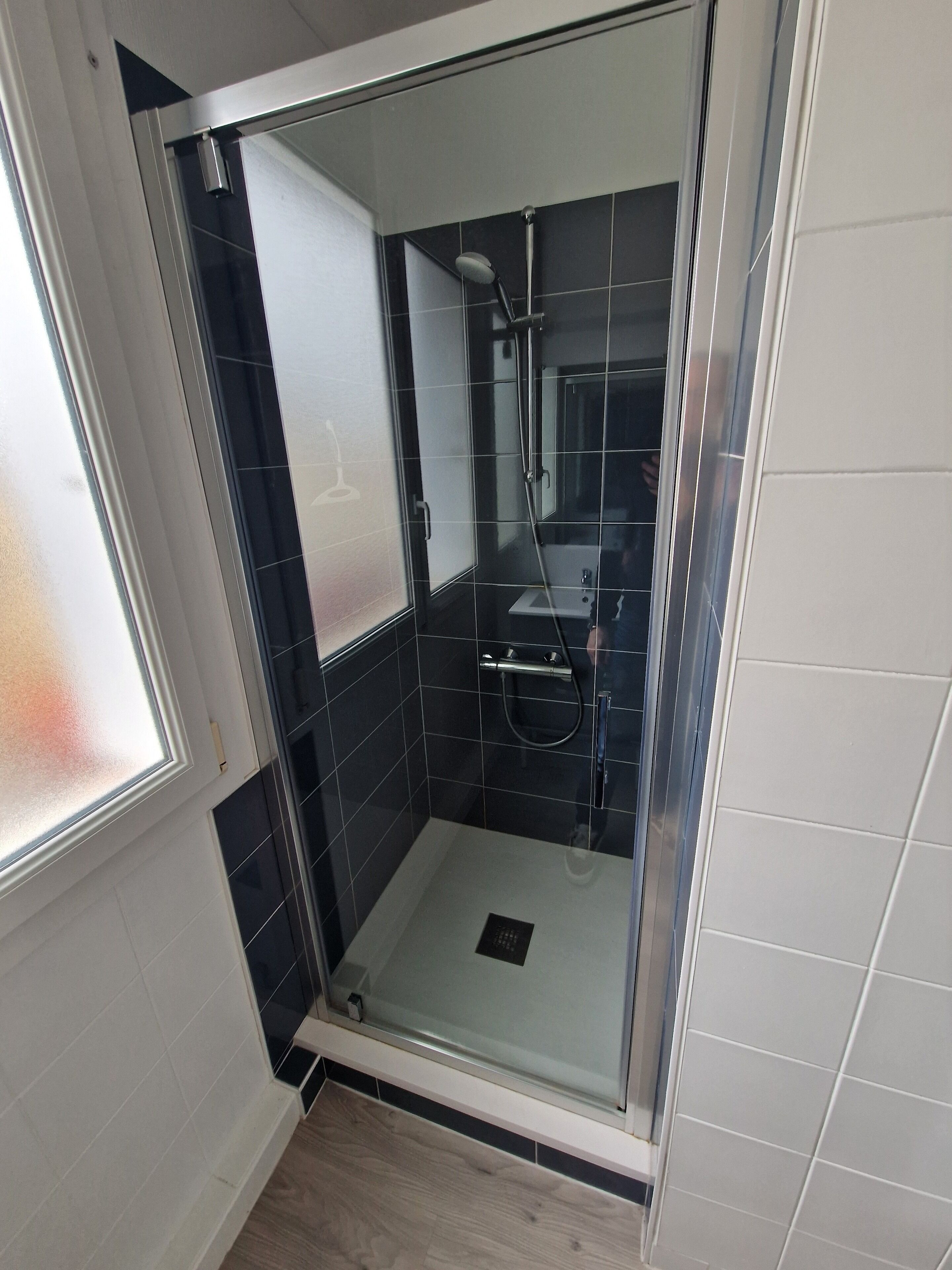 Een glazen douchecabine met een handdouche en een handdouche.