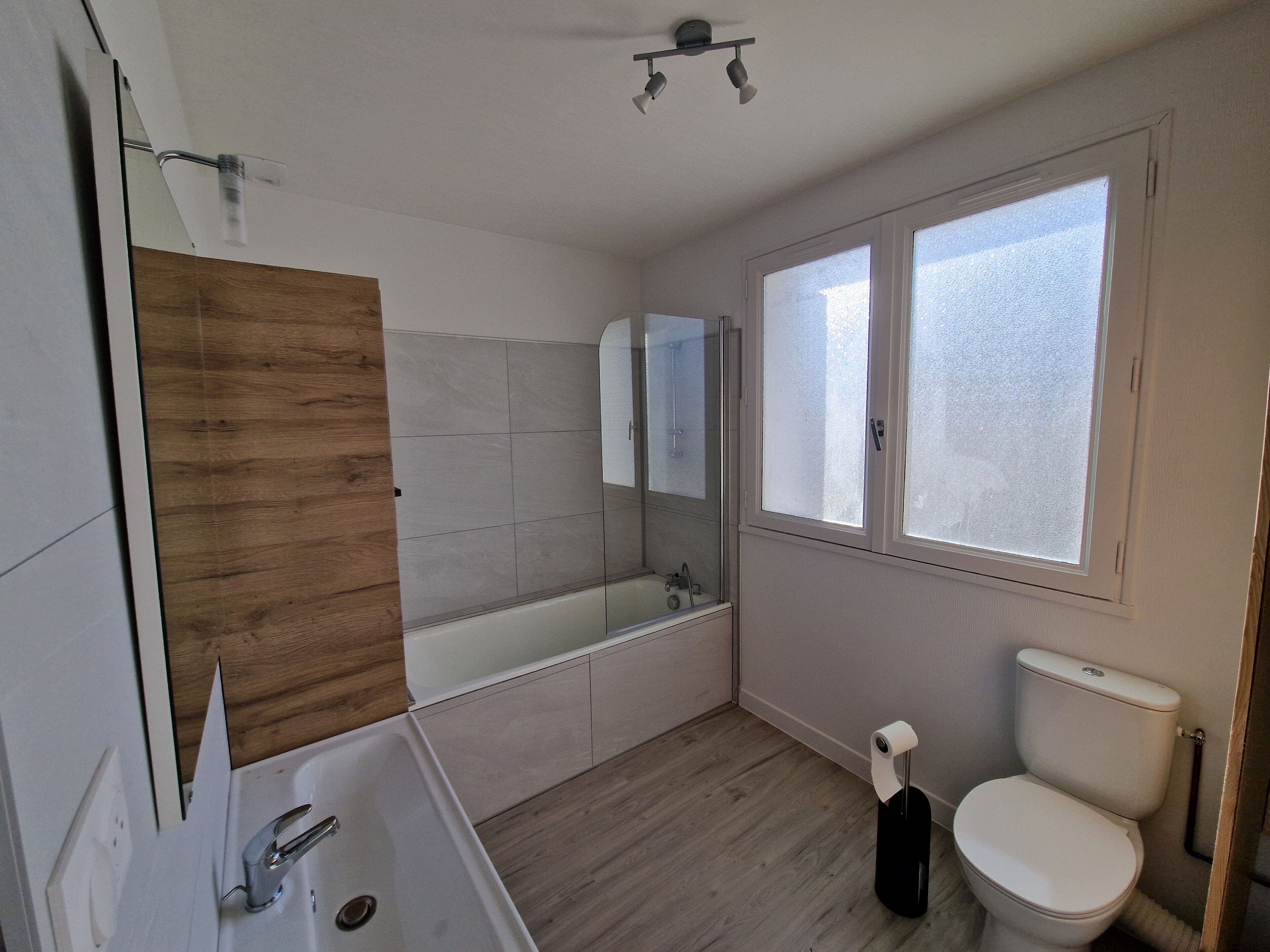 Et moderne badeværelse med badekar, toilet og et stort spejl.