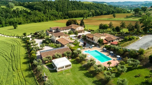 Un vaste domaine comprenant plusieurs bâtiments, une piscine et de vastes étendues de verdure.