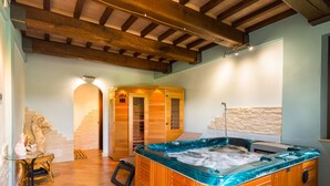 Un espace bien-être comprenant un bain à remous, un sauna en bois et un mur en pierre.