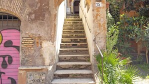 A set of stone steps leading up to a door marked with the number 15, surrounded by greenery and a pink graffiti-covered wall. - Detached house in Trastevere (Roma)