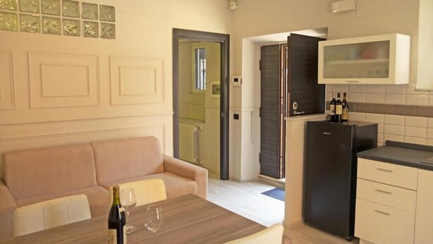 A compact living space with a kitchenette, a dining area with a table and chairs, and a sofa. - Detached house in Trastevere (Roma)