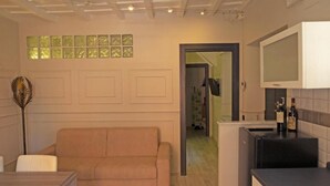 A modern kitchen with a built-in oven, a dining area with a wooden table and a beige sofa, and a hallway leading to another room. - Detached house in Trastevere (Roma)
