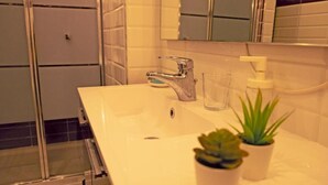 A bathroom with a white sink, a mirror, a glass, and two potted plants. - Detached house in Trastevere (Roma)