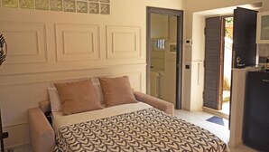 A bedroom with a bed, a sofa, a door leading to a bathroom, and a small kitchenette. - Detached house in Trastevere (Roma)