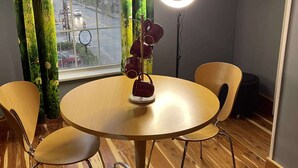 Una habitación con una mesa redonda de madera, dos sillas, una luz de aro y una ventana con cortinas.
