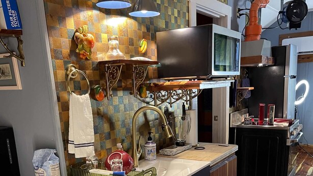 Una cocina con una isla de madera, horno empotrado y microondas.